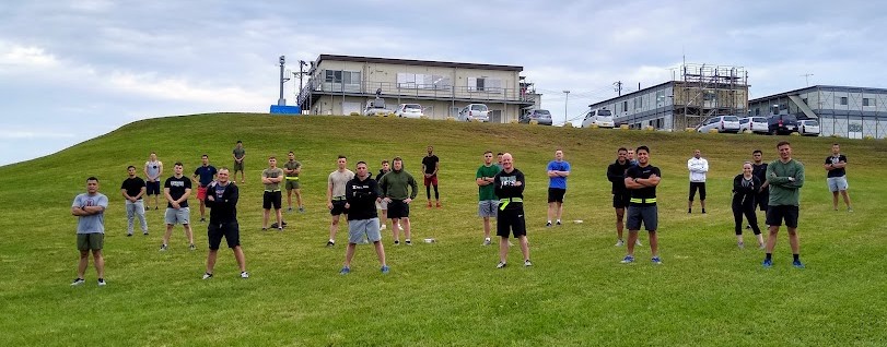 Military team standing on grassy hill during COVID-19 pandemic